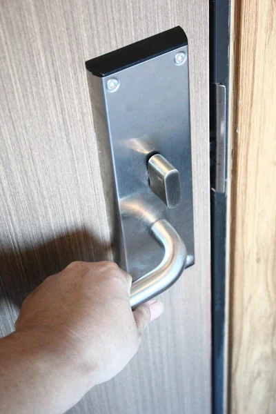 Hand opening a door with a keyhole in a hotel room.