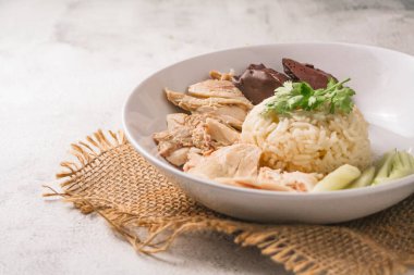 Kişniş, salatalık ve siyah arka planda tavuk çorbası ile birlikte Hainanese tavuğu pilavı. Doğu ve Güneydoğu Asya 'daki yerel yiyecekler