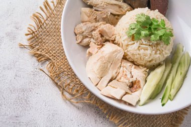 Kişniş, salatalık ve siyah arka planda tavuk çorbası ile birlikte Hainanese tavuğu pilavı. Doğu ve Güneydoğu Asya 'daki yerel yiyecekler