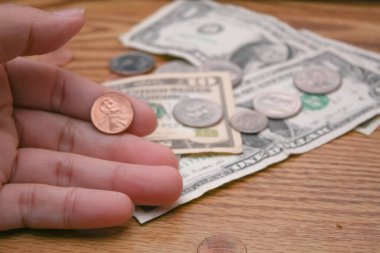 A man's hand is holding a 25 cent coin. Dollar currency, scraps, poor people, money management, currency. clipart