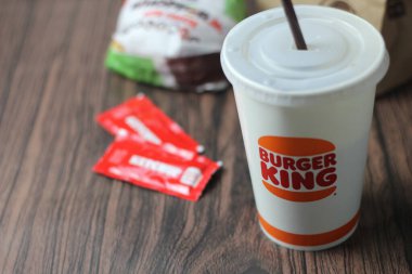 Bangkok, Tayland - 23 Mart 2023 - Burger King seti, Whopper ve meşrubatlar koyu kahverengi ahşap masaya yerleştirildi.