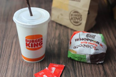 Bangkok, Tayland - 23 Mart 2023 - Burger King seti, Whopper ve meşrubatlar koyu kahverengi ahşap masaya yerleştirildi.