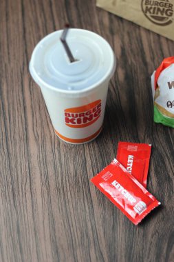 Bangkok, Tayland - 23 Mart 2023 - Burger King seti, Whopper ve meşrubatlar koyu kahverengi ahşap masaya yerleştirildi.