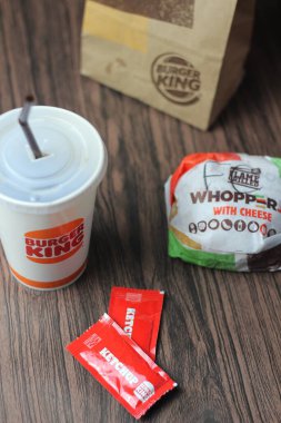 Bangkok, Tayland - 23 Mart 2023 - Burger King seti, Whopper ve meşrubatlar koyu kahverengi ahşap masaya yerleştirildi.