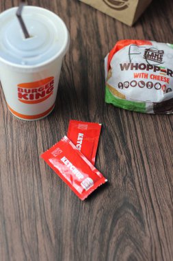 Bangkok, Tayland - 23 Mart 2023 - Burger King seti, Whopper ve meşrubatlar koyu kahverengi ahşap masaya yerleştirildi.