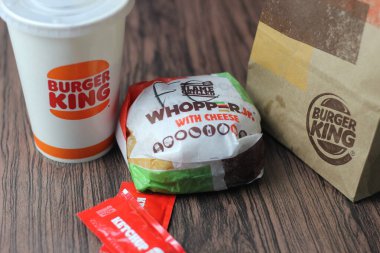 Bangkok, Tayland - 23 Mart 2023 - Burger King seti, Whopper ve meşrubatlar koyu kahverengi ahşap masaya yerleştirildi.