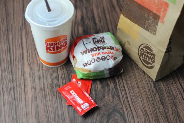 Bangkok, Tayland - 23 Mart 2023 - Burger King seti, Whopper ve meşrubatlar koyu kahverengi ahşap masaya yerleştirildi.