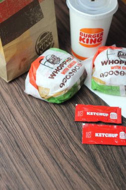 Bangkok, Tayland - 23 Mart 2023 - Burger King seti, Whopper ve meşrubatlar koyu kahverengi ahşap masaya yerleştirildi.