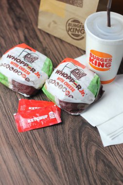 Bangkok, Tayland - 23 Mart 2023 - Burger King seti, Whopper ve meşrubatlar koyu kahverengi ahşap masaya yerleştirildi.