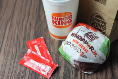 Bangkok, Tayland - 23 Mart 2023 - Burger King seti, Whopper ve meşrubatlar koyu kahverengi ahşap masaya yerleştirildi.