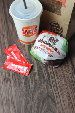 Bangkok, Tayland - 23 Mart 2023 - Burger King seti, Whopper ve meşrubatlar koyu kahverengi ahşap masaya yerleştirildi.