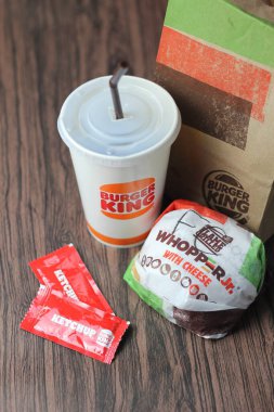 Bangkok, Tayland - 23 Mart 2023 - Burger King seti, Whopper ve meşrubatlar koyu kahverengi ahşap masaya yerleştirildi.