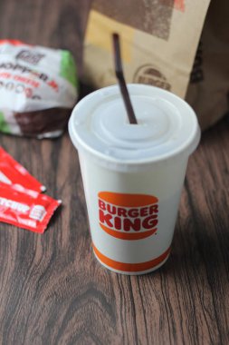 Bangkok, Tayland - 23 Mart 2023 - Burger King seti, Whopper ve meşrubatlar koyu kahverengi ahşap masaya yerleştirildi.