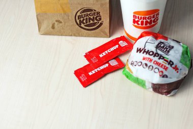 WASHINGTON - ABD - 17 Ağustos 2024 - Klasik bir Burger King yemeği - Peynirli Whopper Jr. bir fincan soda, ketçap paketleri ve kahverengi bir kese kağıdı.