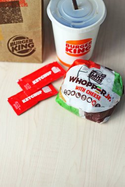 WASHINGTON - ABD - 17 Ağustos 2024 - Peynirli Whopper Jr. 'ın yakın çekimi, Burger King içeceği ve beyaz bir masada ketçap paketleri.