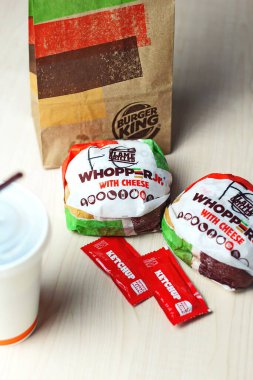 WASHINGTON - ABD - 17 Ağustos 2024 Klasik bir Burger King yemek Whopper Jr. içeceği, ketçap paketleri ve kahverengi bir kese kağıdının detayları.