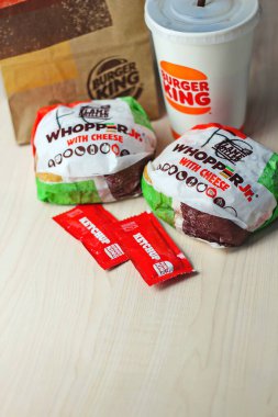 WASHINGTON - ABD - 17 Ağustos 2024 Klasik bir Burger King yemek Whopper Jr. içeceği, ketçap paketleri ve kahverengi bir kese kağıdının detayları.