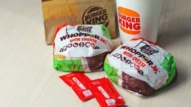 WASHINGTON - ABD - 17 Ağustos 2024 Klasik bir Burger King yemek Whopper Jr. içeceği, ketçap paketleri ve kahverengi bir kese kağıdının detayları.
