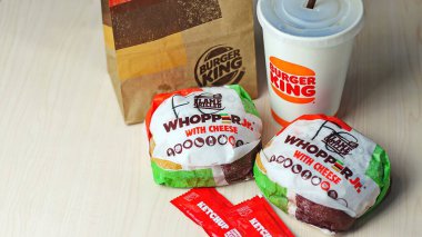 WASHINGTON - ABD - 17 Ağustos 2024 Klasik bir Burger King yemek Whopper Jr. içeceği, ketçap paketleri ve kahverengi bir kese kağıdının detayları.