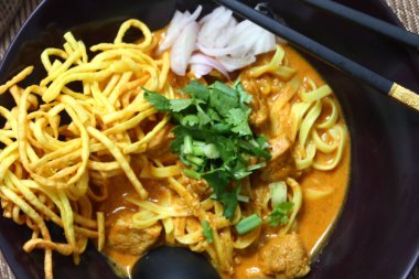 Bir kase Khao Soi, Hint cevizli köri çorbasıyla yıkanmış yumurta erişteli Kuzey Tayland şehriye çorbası üzerine çıtır erişte, hardal turşusu ve taze kişniş..