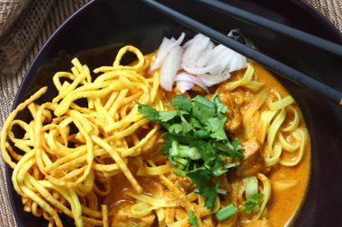 Altın yumurtalı erişte ve canlı yeşil süslemeler bu ağız sulandıran Khao Soi 'deki zengin, kremalı köri' ye karşı güzel bir tezat oluşturuyor..