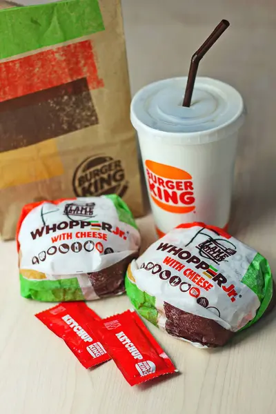 WASHINGTON - ABD - 17 Ağustos 2024 Klasik bir Burger King yemek Whopper Jr. içeceği, ketçap paketleri ve kahverengi bir kese kağıdının detayları.