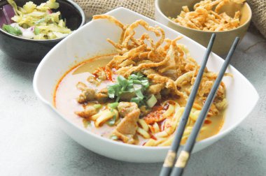 Hint cevizi sütlü erişte, Khao Soi Moo dediğimiz Tayland yemeği, soğan, domuz eti, turşu ve hindistan cevizi sütü içeriyor..