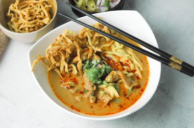 Hint cevizi sütlü erişte, Khao Soi Moo dediğimiz Tayland yemeği, soğan, domuz eti, turşu ve hindistan cevizi sütü içeriyor..