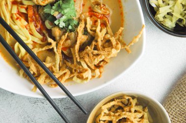 Hint cevizi sütlü erişte, Khao Soi Moo dediğimiz Tayland yemeği, soğan, domuz eti, turşu ve hindistan cevizi sütü içeriyor..