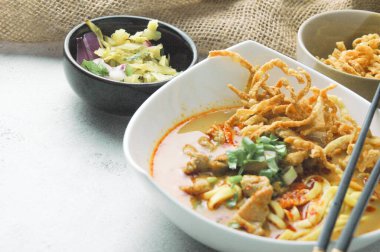 Hint cevizi sütlü erişte, Khao Soi Moo dediğimiz Tayland yemeği, soğan, domuz eti, turşu ve hindistan cevizi sütü içeriyor..