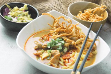 Hint cevizi sütlü erişte, Khao Soi Moo dediğimiz Tayland yemeği, soğan, domuz eti, turşu ve hindistan cevizi sütü içeriyor..