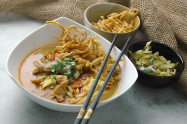 Hint cevizi sütlü erişte, Khao Soi Moo dediğimiz Tayland yemeği, soğan, domuz eti, turşu ve hindistan cevizi sütü içeriyor..