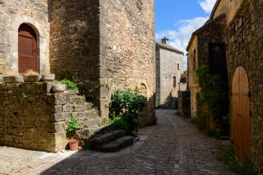 Bu manzara fotoğrafı Avrupa 'da, Fransa' da, Occitania 'da, Aveyron' da, La Couvertoirade 'da, yazın çekildi. Ortaçağ köyünün sokaklarını görüyoruz, güneşin altında..