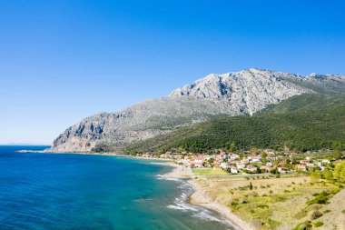 Bu manzara fotoğrafı Avrupa 'da, Yunanistan' da, Aetolia Acarnania 'da, Kato Vasiliki' de yaz aylarında İyon Denizi tarafından Patras 'a doğru çekildi. Kayalık sahilde yeşil kırsalın ortasında, güneşin altında şehri görüyoruz..