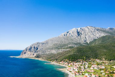 Bu manzara fotoğrafı Avrupa 'da, Yunanistan' da, Aetolia Acarnania 'da, Kato Vasiliki' de yaz aylarında İyon Denizi tarafından Patras 'a doğru çekildi. Kayalık sahilde yeşil kırsalın ortasında, güneşin altında şehri görüyoruz..