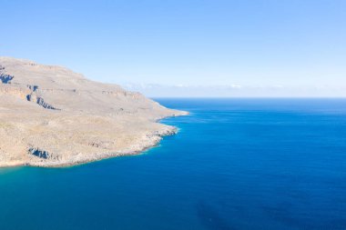 Bu manzara fotoğrafı Avrupa 'da, Yunanistan' da, Girit 'te, Sitia' ya doğru, Akdeniz 'in kıyısında, yazın çekildi. Kurak kayalık sahili ve dağları görüyoruz, güneşin altında..