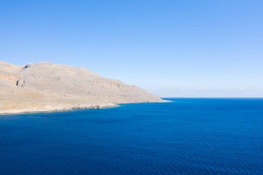 Bu manzara fotoğrafı Avrupa 'da, Yunanistan' da, Girit 'te, Sitia' ya doğru, Akdeniz 'in kıyısında, yazın çekildi. Kurak kayalık sahili ve dağları görüyoruz, güneşin altında..