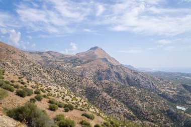 Bu manzara fotoğrafı Avrupa 'da, Yunanistan' da, Girit 'te, Akdeniz kıyısında, yazın çekildi. Kırsalda, güneşin altında kayalık ve kurak dağlar görüyoruz..