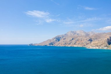 Bu manzara fotoğrafı Avrupa 'da, Yunanistan' da, Girit 'te, Tsoutsouros' ta, Akdeniz 'in kıyısında, yazın çekildi. Şehir merkezini, kurak dağların eteğinde, güneşin altında görüyoruz..