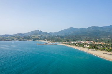 Bu manzara fotoğrafı Avrupa 'da, Fransa' da, Occitanie 'de, Pireneler' de, Argeles 'te, Akdeniz' in kıyısında, yazın çekildi. Yeşil sahilde, güneşin altında beyaz kumsal görüyoruz..