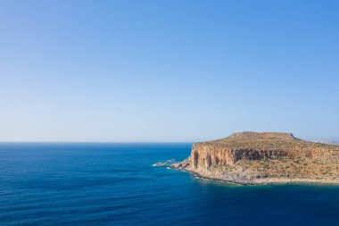 Bu manzara fotoğrafı Avrupa 'da, Yunanistan' da, Girit 'te, Balos' ta, Akdeniz 'in kıyısında, yazın çekildi. Kayalık kayalıkların dibinde, güneşin altında pembe yansımaları olan kumlu bir sahil görüyoruz..