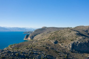 Bu manzara fotoğrafı Avrupa 'da, Yunanistan' da, Peloponnese 'de, Argolis' te, Nafplio 'da, Myrto sahilinde, yazın çekildi. Kurak kayalık sahili ve yeşil kırsalını görüyoruz. Güneşin altında, küçük plajların kenarında..