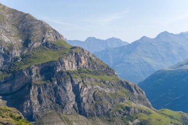 Bu manzara fotoğrafı Avrupa 'da, Fransa' da, Occitanie 'de, Hautes-Pyrenees' de, yazın çekildi. Kırsalın ortasında, güneşin altında kurak ve kayalık dağlar görüyoruz..