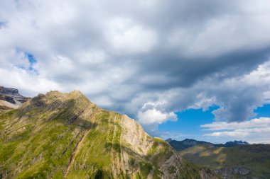 Bu manzara fotoğrafı Avrupa 'da, Fransa' da, Occitanie 'de, Hautes-Pyrenees' de, yazın çekildi. Kırsalın ortasında, güneşin altında kurak ve kayalık dağlar görüyoruz..