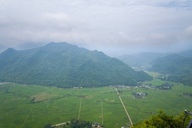 Bu manzara fotoğrafı Asya 'da, Vietnam' da Tonkin 'de, Hanoi' de, Mai Chau 'da, yazın çekildi. Vadide, güneşin altında yeşil pirinç tarlalarının etrafındaki dağları görüyoruz..