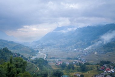 Bu manzara fotoğrafı Asya 'da, Vietnam' da, Tonkin 'de, Sapa' da Lao Cai 'de, yazın çekildi. Yeşil tropikal dağlarda, bulutların altında yeşil ve sarı pirinç teraslarını görüyoruz..