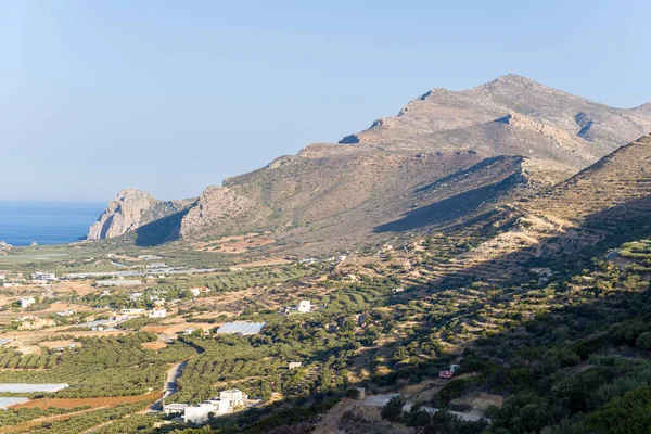 Bu manzara fotoğrafı Avrupa 'da, Yunanistan' da, Girit 'te Kissamos' a doğru, Chania 'ya doğru, Akdeniz' in kıyısında, yazın çekildi. Kırsalda, güneşin altında seraların ve zeytin ağaçlarının kıyısındaki kumsalı görüyoruz..