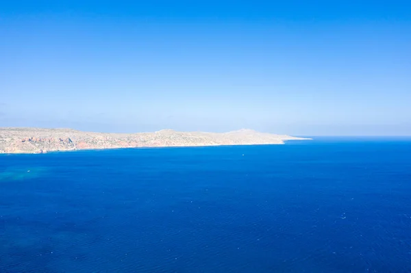 This landscape photo was taken, in Europe, in Greece, in Crete, towards Sitia, At the edge of the Mediterranean Sea, in summer. We see the arid rocky coast and the fine sandy beach of Vai, under the sun.