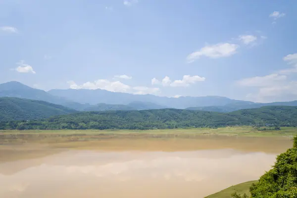 This landscape photo was taken, in Asia, in Vietnam, in Tonkin, between Dien Bien Phu and Lai Chau, in summer. We see The Red River in the middle of the green mountains, under the Sun.