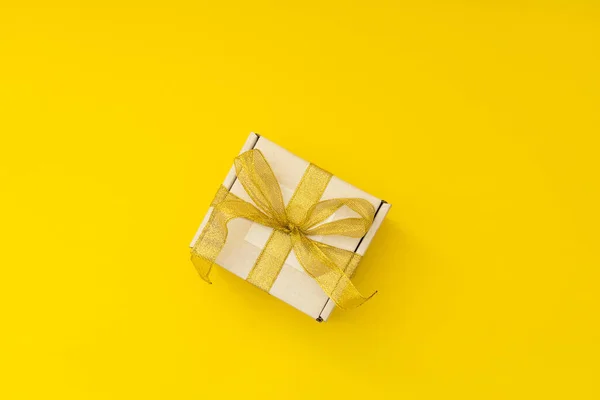 New Year\'s gift in a white box with a golden ribbon on a yellow background
